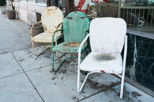 Vintage lawn chairs displayed outside a shop.