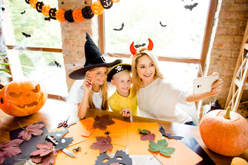 Shot portrait of three at halloween party, mommy and her cheerful kids - blond small witch and...