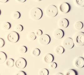 Scattered white buttons flat lay overhead view on white