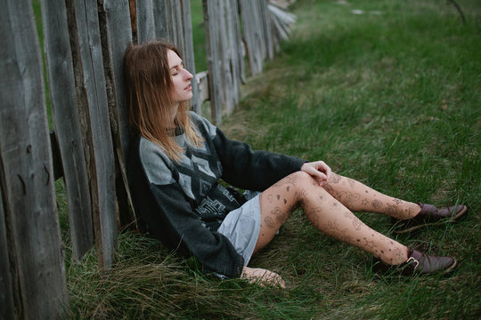 The girl has a rest from an old rustic fence after a walk
