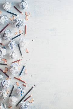 Flat lay frame with copy space. Writer workplace with minimalist pattern. Crumpled paper balls with pencils on a white wooden background, creative writing concept.