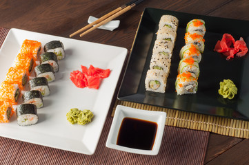Sushi on a black and white plate, on a wooden mat