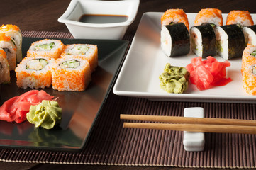 Sushi on a black and white plate, on a wooden mat