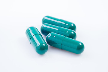 Capsules of green herbal supplement product isolated on white background