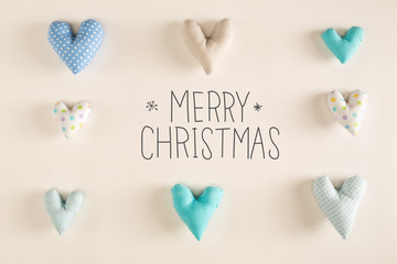 Merry Christmas message with blue heart cushions on a white paper background
