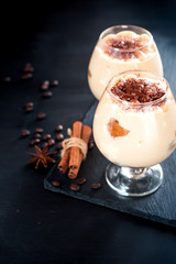 tiramisu in a glass decorated with coffee beans on a dark background, space for text