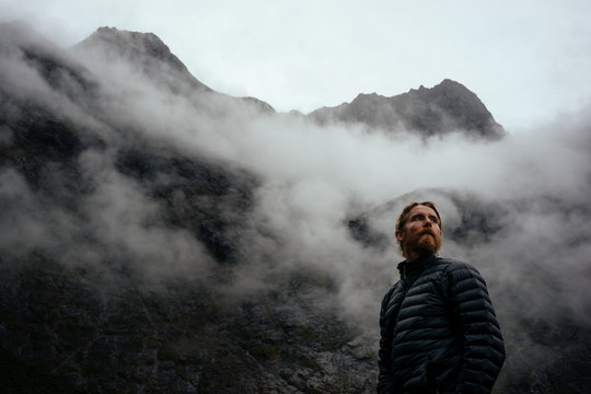 Man in his down jacket looking towards the cold foggy sky as the weather changes