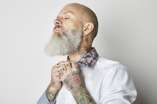 Studio portrait of man with tattoos fixing collar