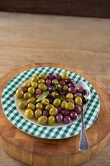 Marinated olives with herbs on wooden board