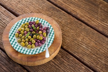 Marinated olives with herbs on wooden board