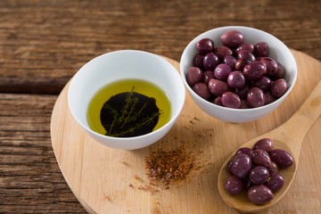 Purple olives, oil and wooden spoon on table