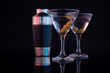 Cocktail martini with olives and shaker on table