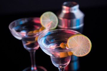 Cocktail martini with olives and shaker on table