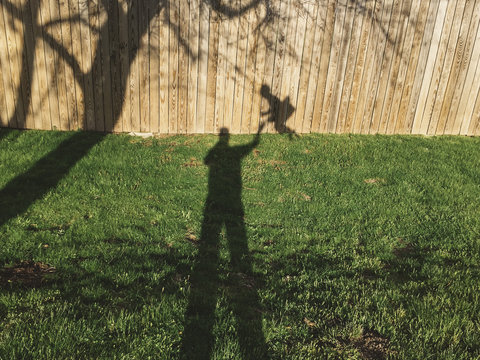 Shadow of man taking selfie with boy on swing