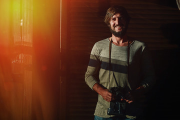 Smiling bearded guy with a camera posing in sunlight