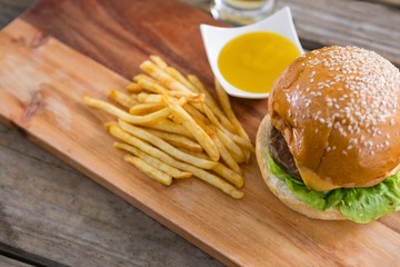 Hamburger with fries and dip on cutting board