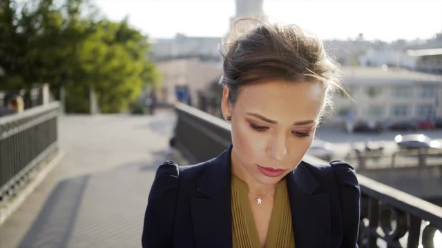 portrain of young business women in black jacket go on the camera on the bridge with cup and paper document in hands
