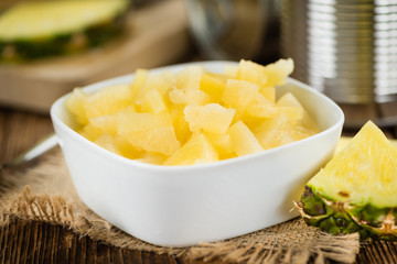 Chopped Pineapple (preserved) on wooden background; selective focus