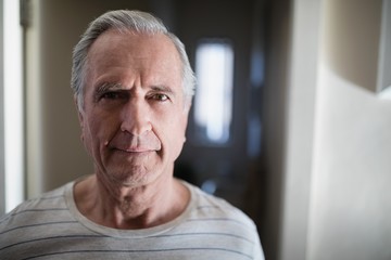 Close-up portrait of senior male patient standing in corridor