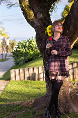 Blonde young woman by the tree holding sunflowers