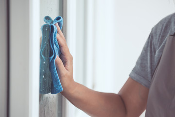 Woman hand cleaning window with rag