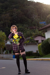 Obraz premium Blodne young woman holding sunflowers by the sunset