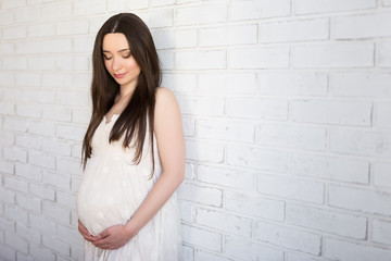 family, pregnancy and parenthood concept - portrait of happy pregnant woman standing over white wall