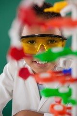 Smiling schoolboy experimenting molecule model in laboratory