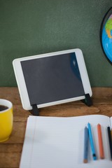 Digital tablet and globe on table in classroom