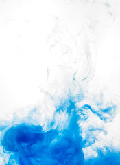 Ink swirl in water isolated on white background. The paint in the water. Soft dissemination a droplets of blue ink in water close-up. Abstract background. Soft focus.