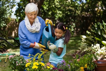 Smiling grandmother and granddaughter watering plants