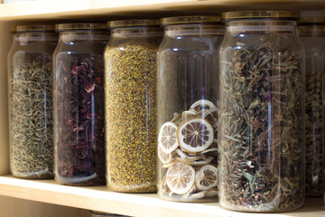 Jars with tea and dried lemon on the shelf