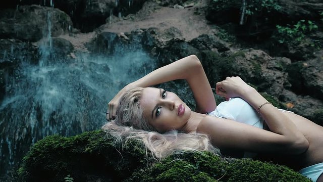 beautiful woman in a bikini standing near a waterfall