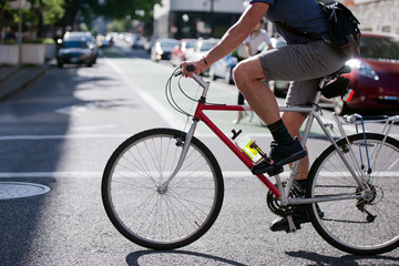 Cyclist running on across the sunny street of modern city