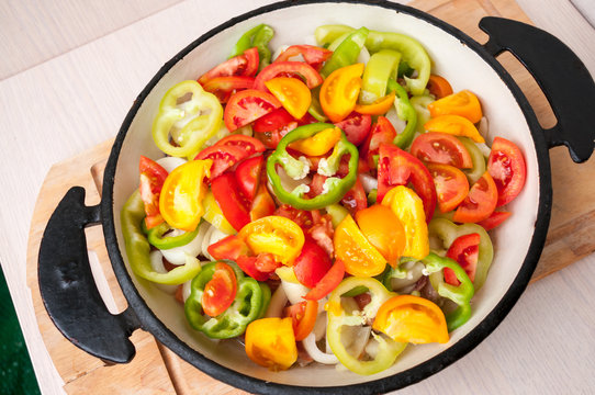 Sliced vegetables in a frying pan stand on table