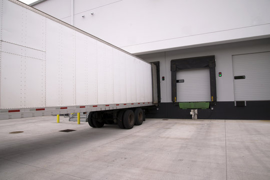 Long Dry Van Semi Trailer Stand With Open Door In Warehouse Dock Gate For Unload