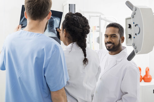 Radiologist With Colleagues Analyzing X-ray In Hospital