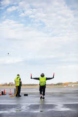 Obraz premium Marshaller Holding Signal Wands While Standing By Colleague On R