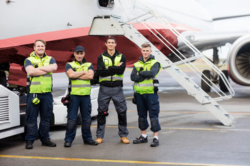 Portrait Of Ground Team Standing Arms Crossed Against Airplane