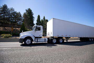 White big rig day cab semi truck and dry van trailer for local delivery and reposition of industrial cargo