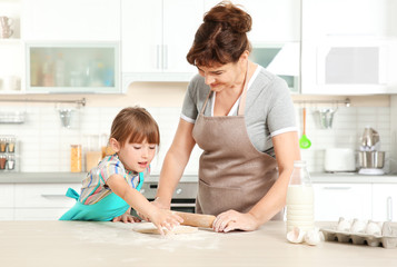 Cute little girl and her grandmother on kitchen
