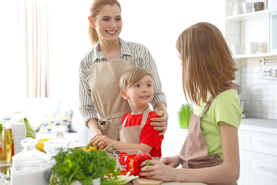 Mother and children making meal together in kitchen. Cooking classes concept