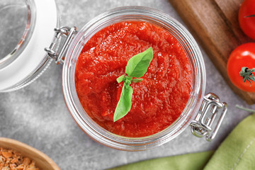Glass jar with tasty tomato sauce for pasta on table