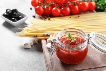 Glass jar with tasty tomato sauce and pasta on table
