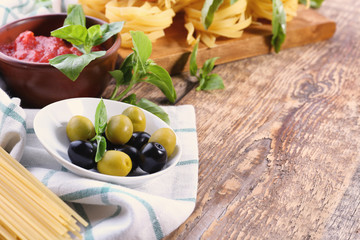 Bowl with tasty olives and tomato sauce for pasta on table