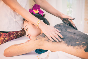 Therapist is scrubbing Charcoal clay scrub cream on women back
