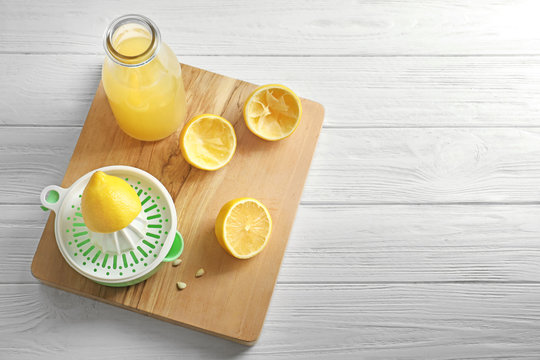 Composition with lemon juice and squeezer on wooden background