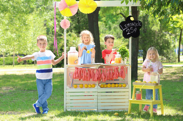 Happy children making lemonade at stand in park - obrazy, fototapety, plakaty