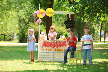 Happy children near lemonade stand in park - obrazy, fototapety, plakaty