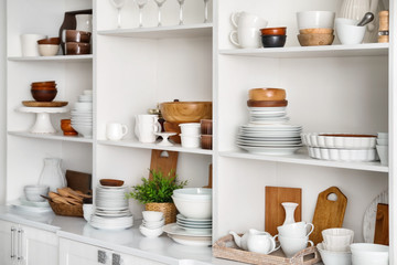 Obraz na płótnie Canvas White storage stand with ceramic and wooden dishware in kitchen